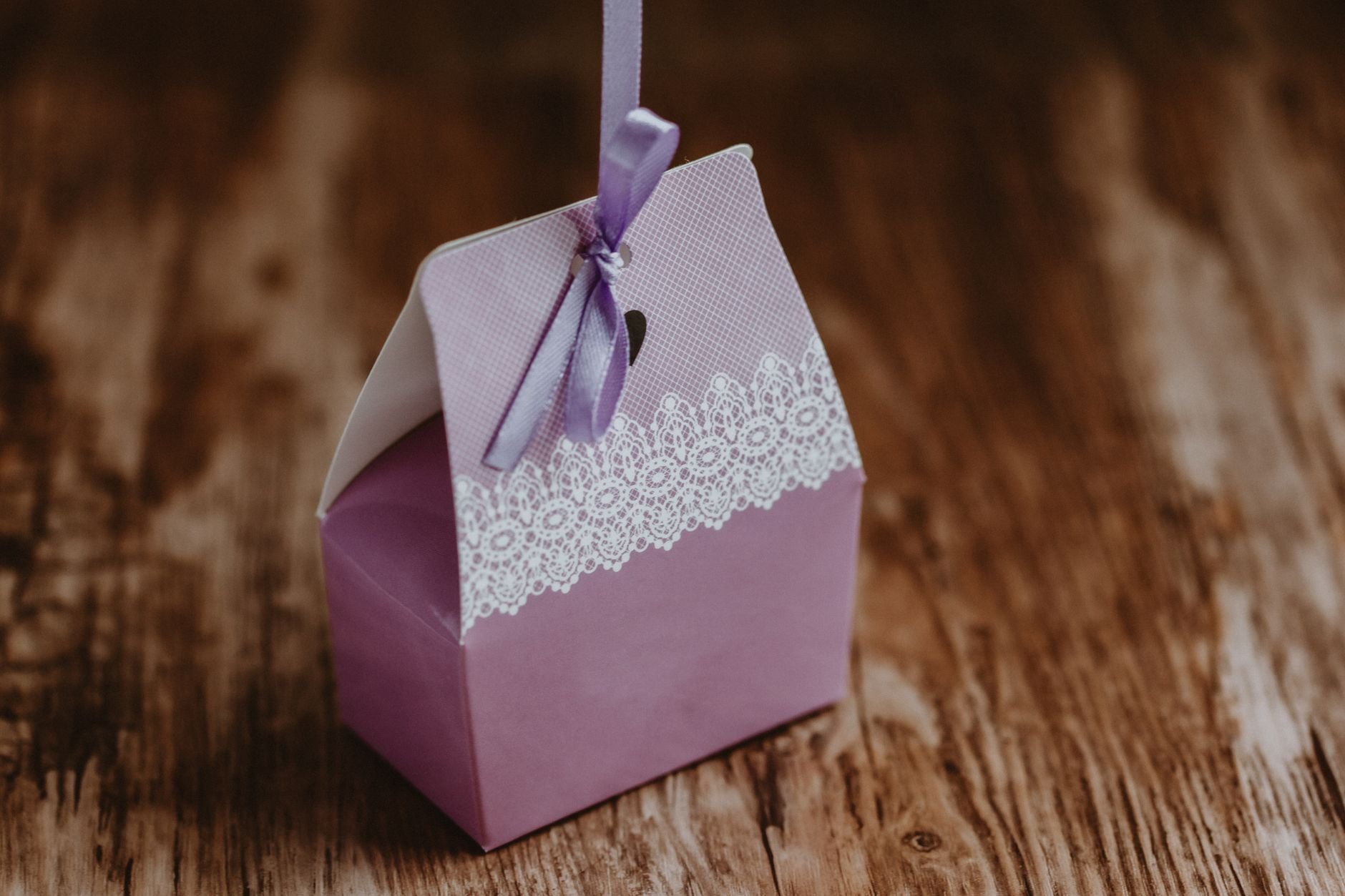 Pink gift box wrapped with purple ribbon on wooden table